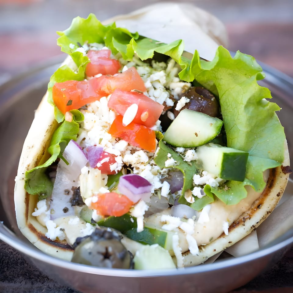 A Mediterranean gyro from Alpha Omega Grill & Bakery, filled with fresh vegetables, feta, and olives.